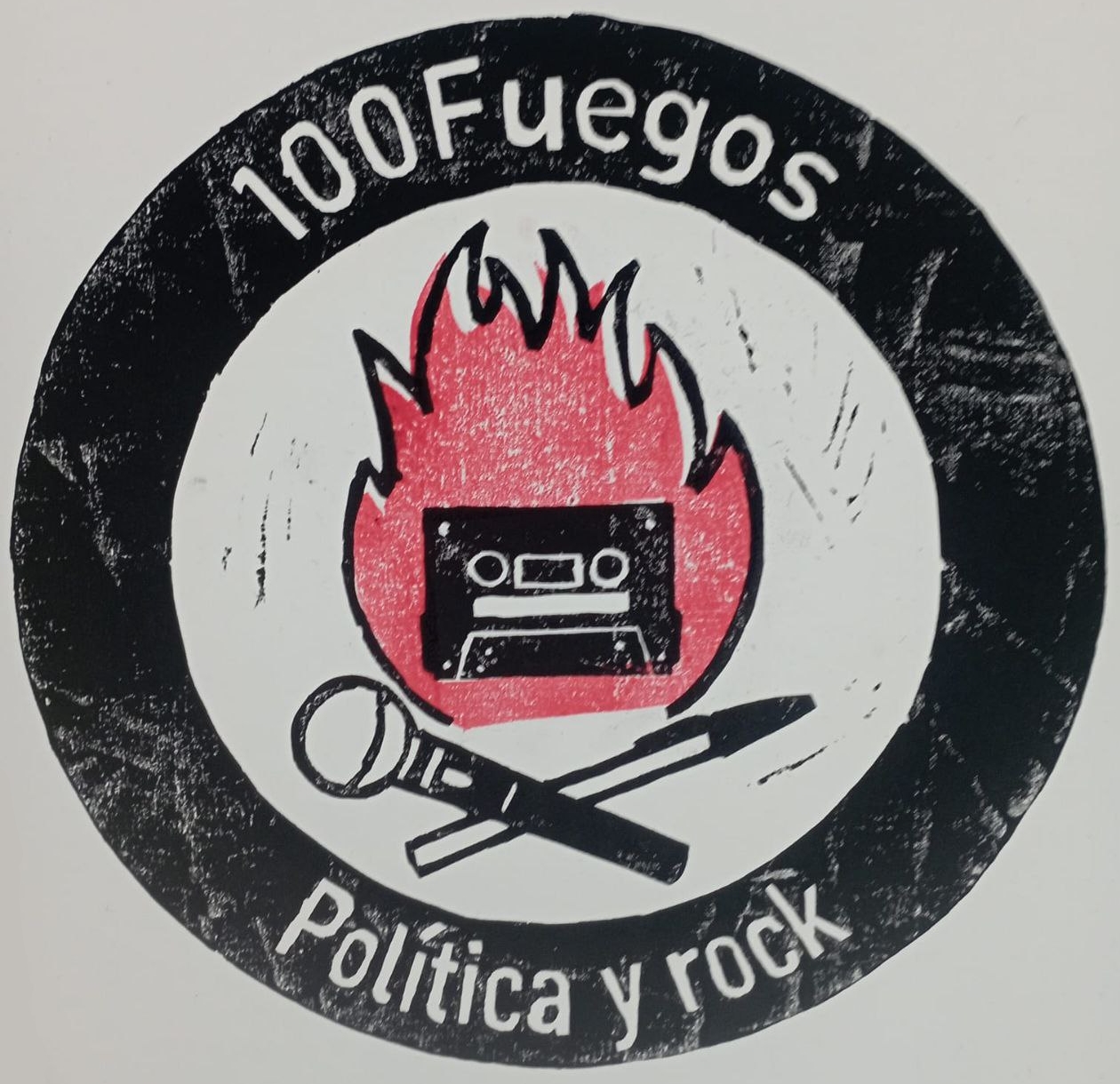 Foto a una lámina con el logo del programa de radio 100Fuegos Política y rock, estampado con tinta negra y roja sobre cartulina blanca. El logo consiste en: Un círculo grueso y negro en el que aparece escrito "100Fuegos" (en la parte superior) "Política y rock" (en la parte inferior). Las letras son gruesas y del color del fondo, el blanco de la cartulina. Dentro de la banda negra, en el centro de la imagen y sobre el fondo blanco, aparecen elementos que recuerdan a una hoguera por cómo están dispuestos. Un boli y un micrófono aparecen cruzados en la parte inferior (a modo de los troncos de madera), y justo encima hay un fuego rojo que dentro tiene una cinta de cassette. Esta disposición también puede recordar a la calavera con tibias cruzadas de los piratas. Cinta, boli y micrófono son de trazo grueso y sencillo, sin apenas detalle. El color rojo de la fogata tiene desfase con respecto a las líneas que tendrían que ser su borde, y hay distintos fallos en la estampación (coloración desigual, así como manchas. También se puede apreciar la textura rugosa del soporte usado.
